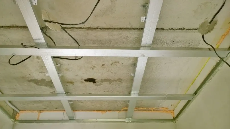 Sufity podwieszane: metalowa konstrukcja profili sufitowych z przewodami i pianką uszczelniającą