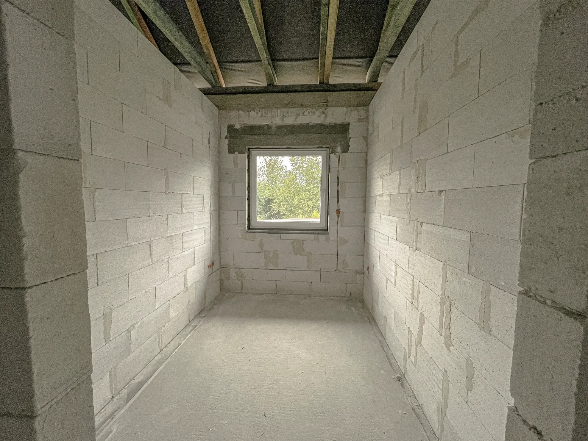 Ściany działowe z surowych bloczków silikatowych w niewykończonym pomieszczeniu z oknem