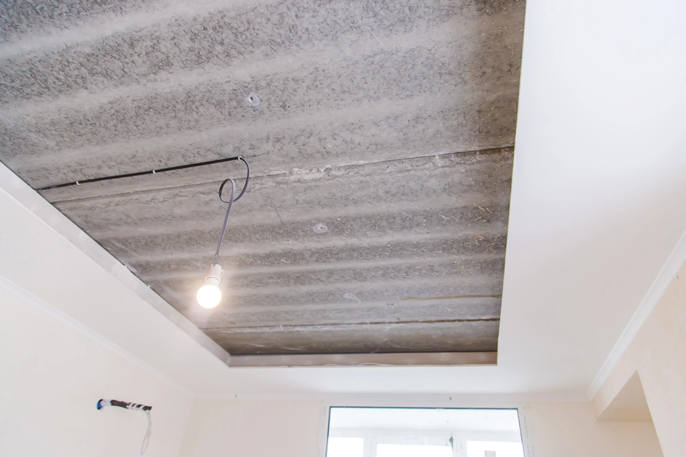 Rozpoczęty montaż sufitu podwieszanego z odsłoniętą płytą stropową i zwisającą żarówką
