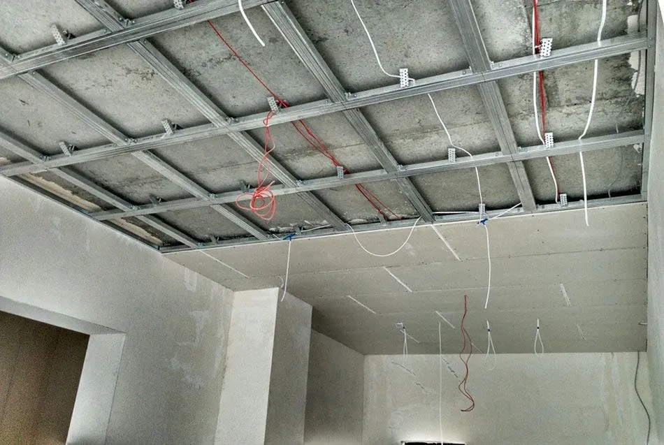 Sufity podwieszane z rusztem metalowym, przewodami elektrycznymi i przykręconymi płytami gk w trakcie montażu