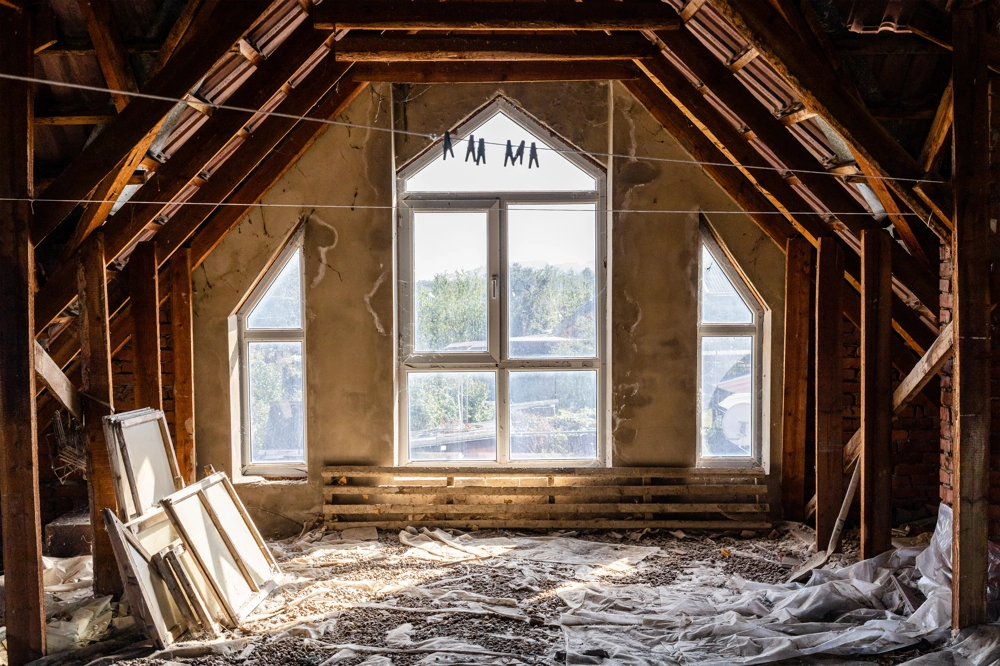 Zabudowa poddasza w surowym stanie z odsłoniętymi krokwiami i przygotowanymi płytami GK